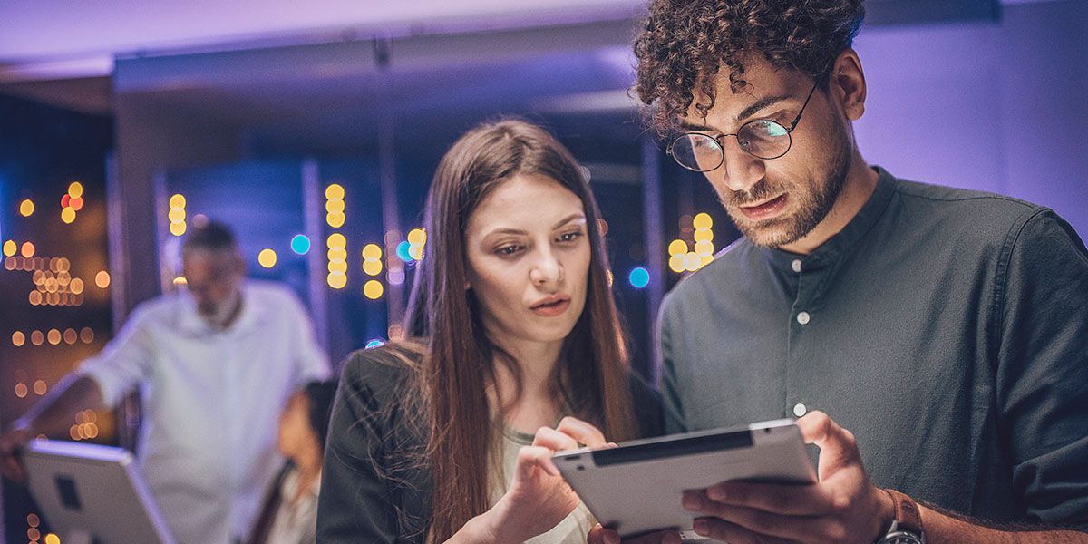 two cybersecurity professionals examine data on a tablet screen