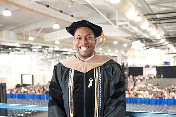 Smiling graduate in full cap and gown at commencement ceremony