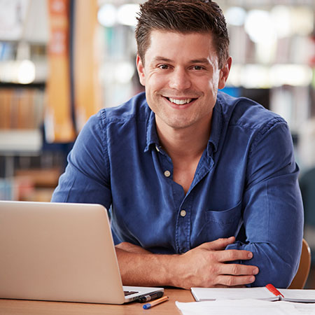 Smiling student seated in front of laptop