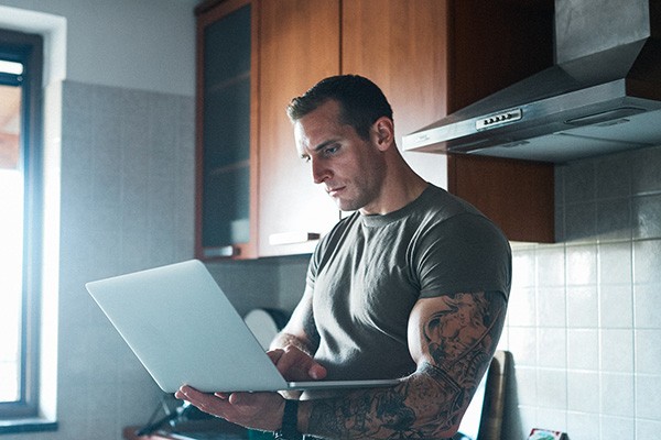 military service member works on a laptop in the kitchen