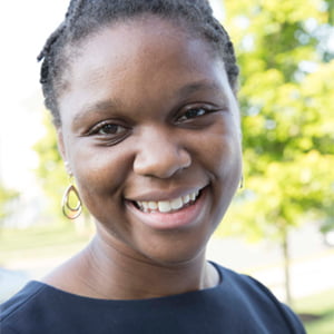 A young African American woman smiles. Her hair is pulled back and she is wearing a black shirt.