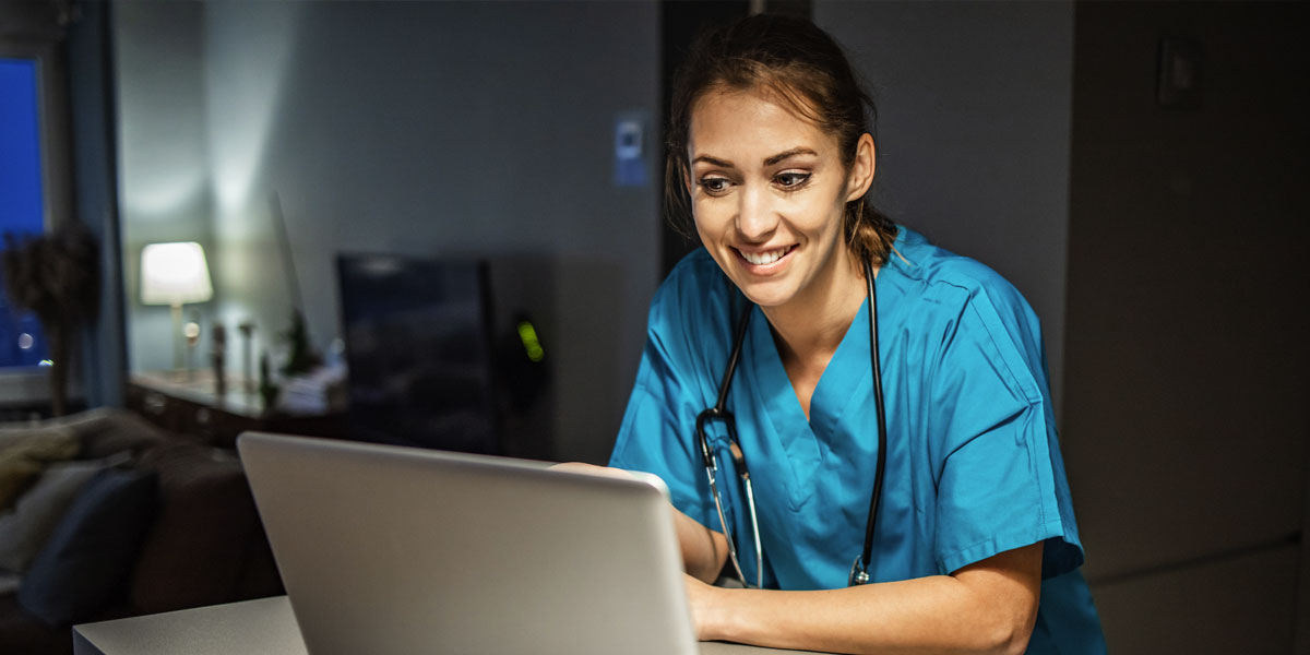 smiling health care professional at home using a laptop computer on a counter