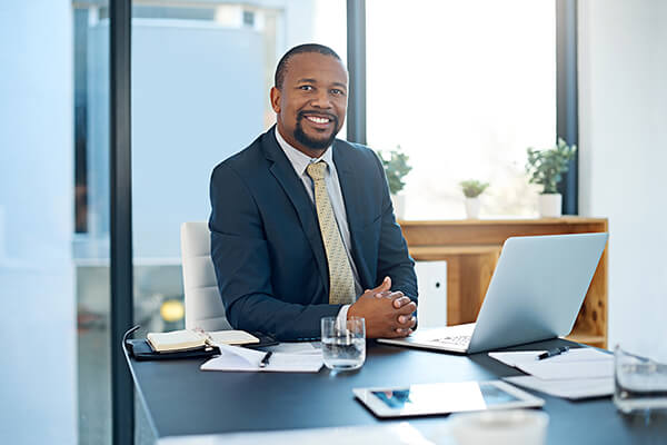 Man in business suit smiles from desk